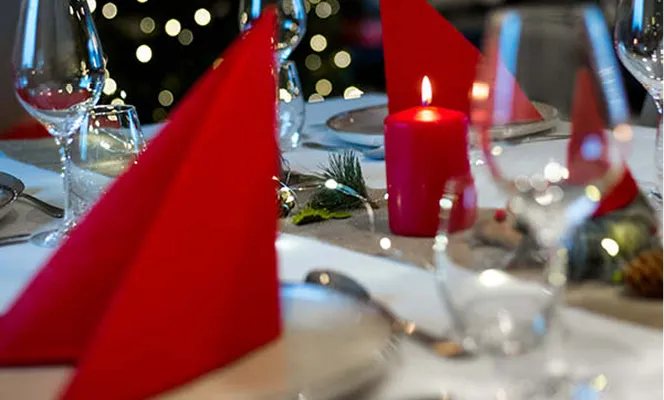 Ett spisebord pyntet med røde servieter og røde kubbelys 